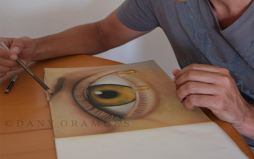 el artista Dany Oramues pintando un ojo surrealista
